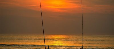 Beach at sunset with fishing poles